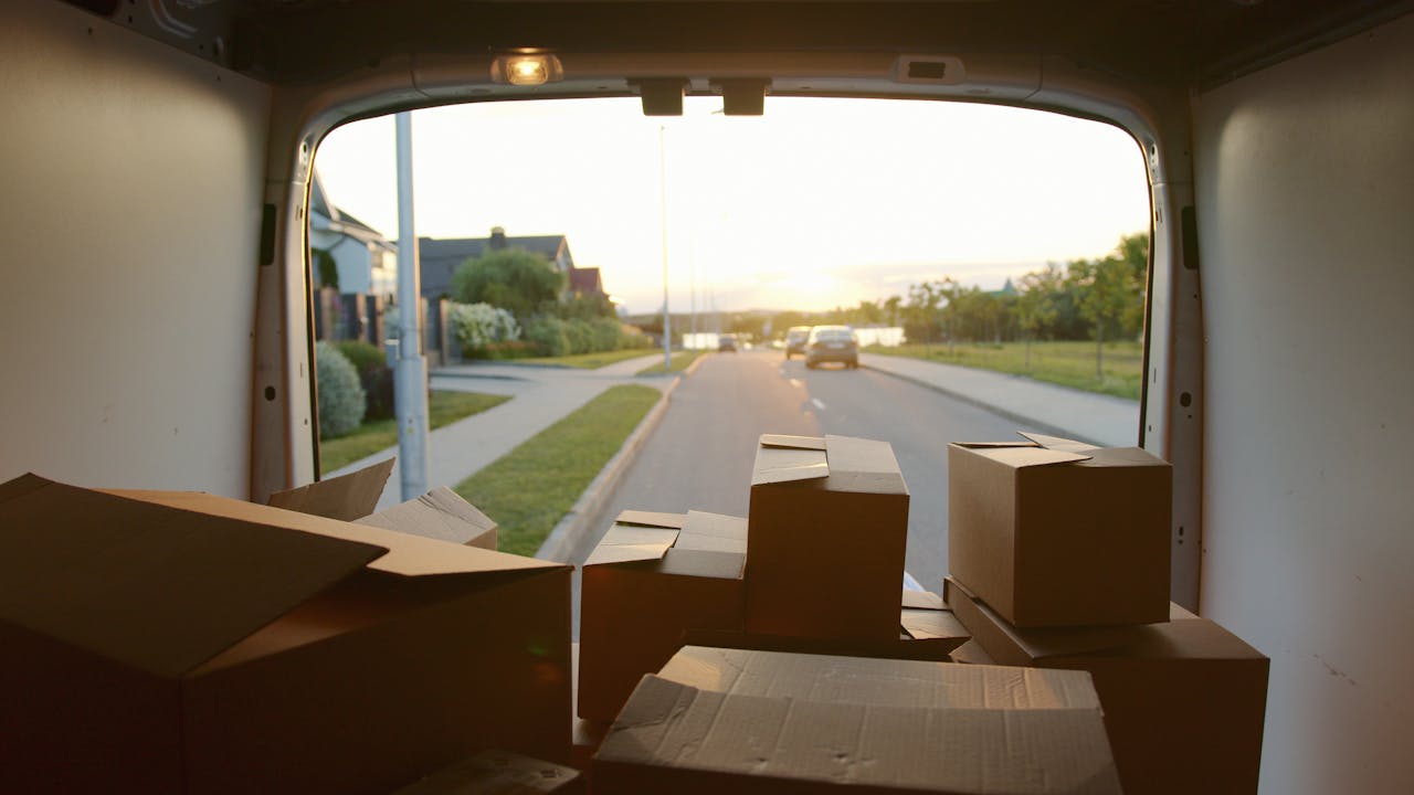 services-03 A scenic view from a delivery van loaded with cardboard boxes at sunset on a suburban street.
