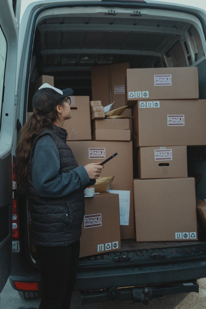 services-04 A female delivery worker organizing packages marked fragile in the back of a delivery van.